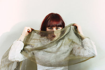 Portrait of young woman standing against wall