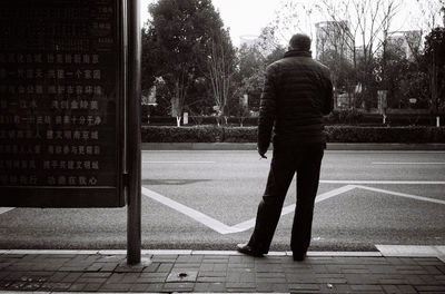 Rear view of man walking on sidewalk in city