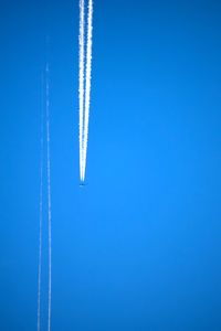 Low angle view of vapor trail against blue sky