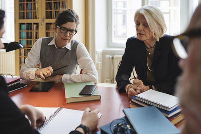 Professionals discussing during meeting while sitting at table in law library