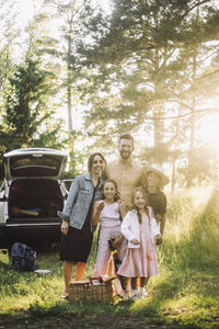 Portrait of happy family standing together on grass during picnic