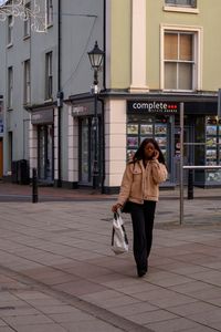 Full length of woman walking on footpath in city