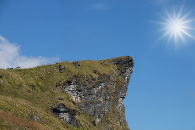 Low angle view of rocks against blue sky on sunny day