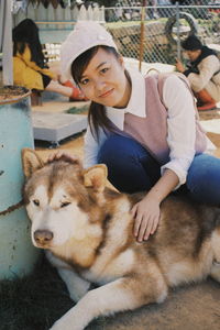 Portrait of smiling young woman sitting by dog