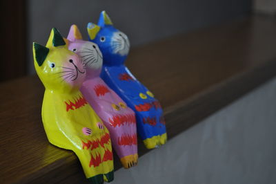 Close-up of cat figurines on wooden railing
