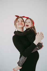 Pregnant mother with her preschool daughter having fun in matching outfits