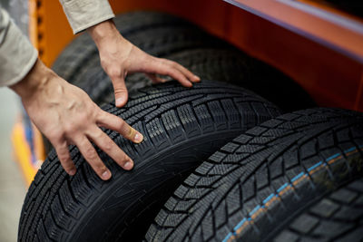 Close-up of a man's hand with car tires in auto shop