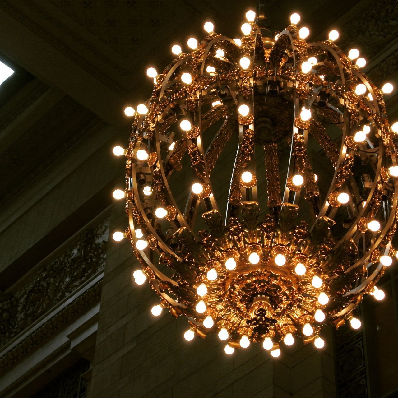 LOW ANGLE VIEW OF ILLUMINATED CHANDELIER HANGING ON BUILDING