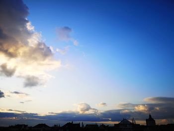 Low angle view of silhouette buildings against blue sky