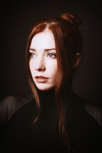 Portrait of young woman against black background