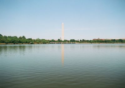 Washington monument by lake against clear sky