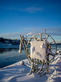 Frozen wheel against sky during winter