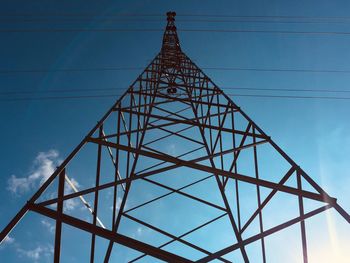 Low angle view of electricity pylon against blue sky