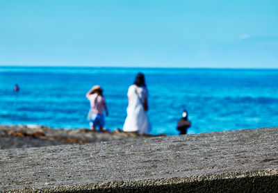 People on beach against blue sky