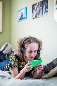 Teenage boy using mobile phone while lying on bed at home