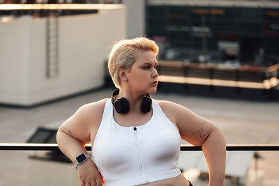 Young woman looking away while standing outdoors