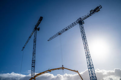 Low angle view of cranes against blue sky