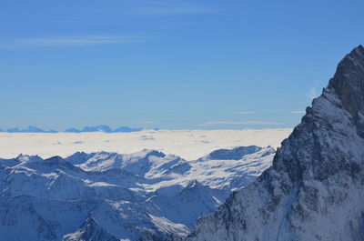 Scenic view of snowcapped mountains against blue sky