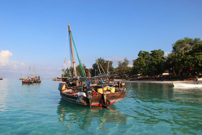 Boats sailing in sea against clear sky