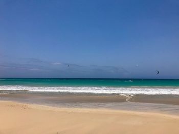 Scenic view of beach against blue sky