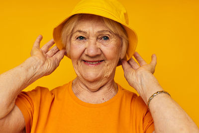 Portrait of young woman against yellow background