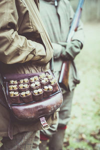 Midsection of hunters standing on field