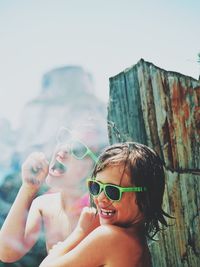 Portrait of happy boy wearing sunglasses against sky
