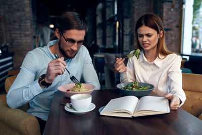 Young man eating food at restaurant table