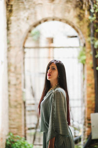 Portrait of young woman standing against building