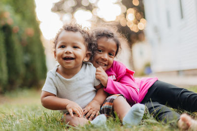 Smiling sibling sitting grass outdoors