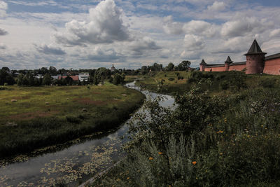 Houses on field by buildings against sky