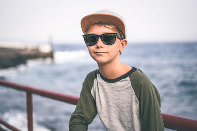 Portrait of man wearing sunglasses standing against sea