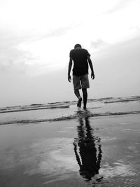 Rear view of man walking at beach