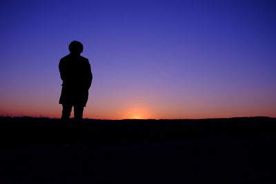 Rear view of silhouette person on landscape against clear sky at dusk