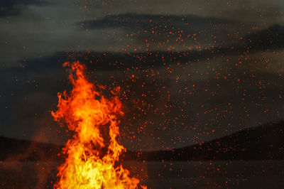 Bonfire against cloudy sky at night