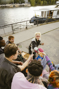 High angle view of non-binary friends sharing pizza near promenade in city