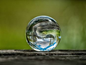 Close-up of crystal ball reflecting wooden figurine on table