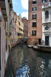 Canal amidst buildings against sky