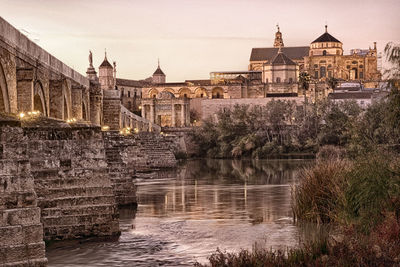 Arch bridge over river against buildings in city