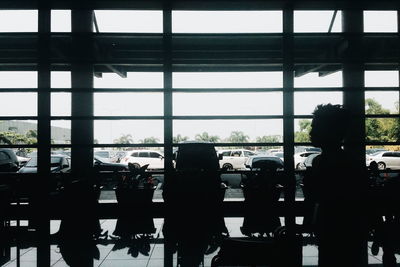 Silhouette people in airport seen through window