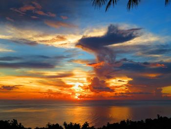 Scenic view of sea against dramatic sky during sunset