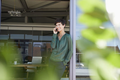 Smiling woman standing at the window talking on cell phone