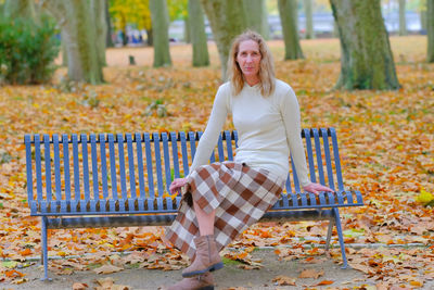 Portrait of smiling woman sitting on bench at park