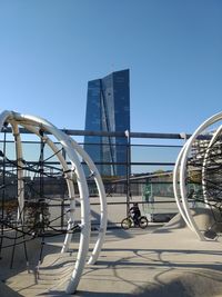 Ferris wheel by modern buildings against clear sky