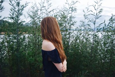 Rear view of woman standing on field against trees