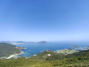 High angle view of townscape by sea against clear blue sky