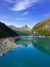 Scenic view of lake and mountains against blue sky