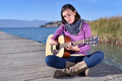 Young man playing guitar on water