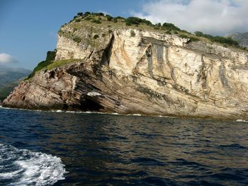 Rock formation by sea against sky