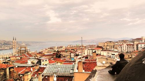 Cityscape and bosphorus against cloudy sky